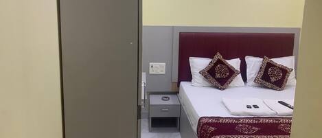 A hotel room with a bed, a nightstand, a drawer, and a wardrobe.