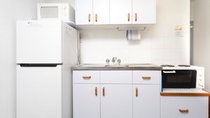 Een keuken met witte kastjes, een koelkast, een gootsteen en een fornuis.
