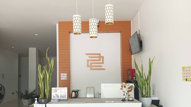 Un espace d'accueil au design moderne, comprenant un comptoir de réception portant l'inscription « RÉCEPTION », un téléviseur fixé au mur et des plantes décoratives.