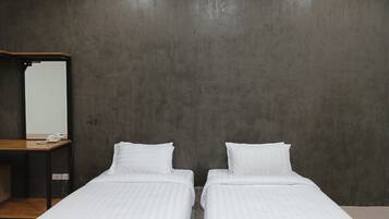 A room with two single beds, a wooden desk, and a mirror on the left wall.