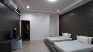 Une chambre d’hôtel moderne équipée de deux lits, d’un bureau et d’une télévision.