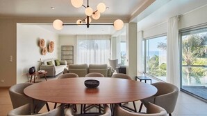 A modern dining area with a round table, six chairs, and a contemporary chandelier.