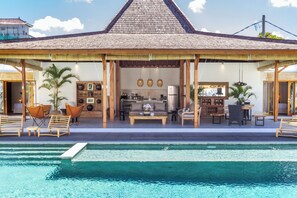 Un área junto a la piscina con un espacio de descanso cubierto, una cocina y un comedor.