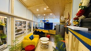 A modern kitchen with a blue countertop, a yellow sofa, and a red ottoman. - Clarence Cottage (Dehradun)