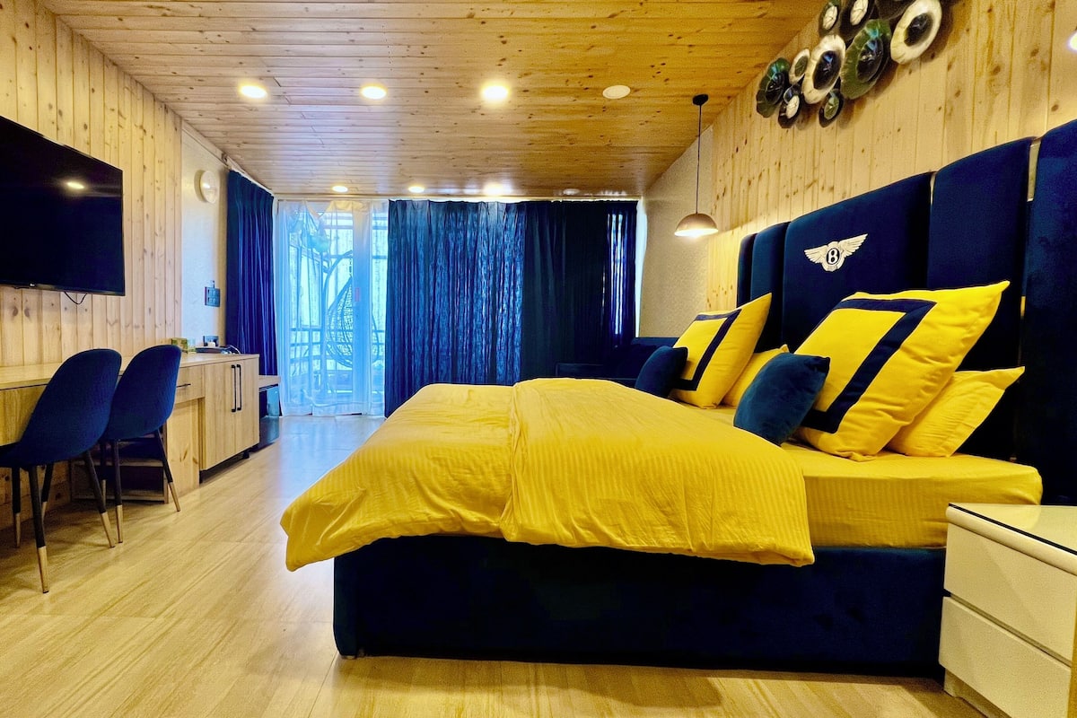 A bedroom with a bed, a TV, a desk, and a chair.