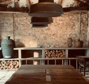 Un intérieur rustique avec un mur en pierre, une table en bois et un luminaire suspendu.