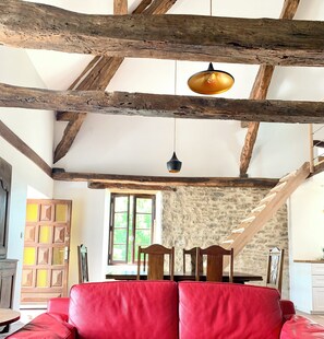 Un intérieur rustique avec des poutres apparentes, un mur en pierre et un canapé en cuir rouge.