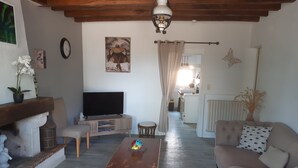 Una sala de estar con televisión, una mesa de centro de madera, un sofá y un comedor al fondo.