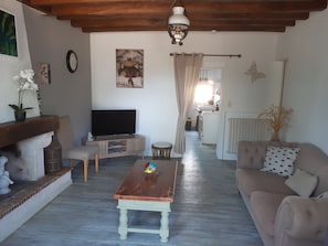 A living room with a television, a wooden coffee table, a sofa, and a dining area in the background.