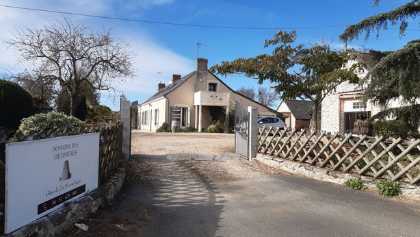 A building with a gated entrance, a signboard, and a gravel driveway leading to the property. - Gîte with terrace and breathtaking view (Beaulieu-sur-Layon)