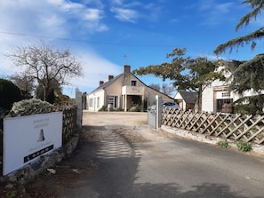 A building with a sign indicating it is a winery, Domaine des Ortières, with a gravel driveway leading to the entrance.