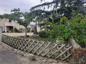Un espace extérieur clos, avec un chemin de gravier, un banc en bois et un mur en pierre.