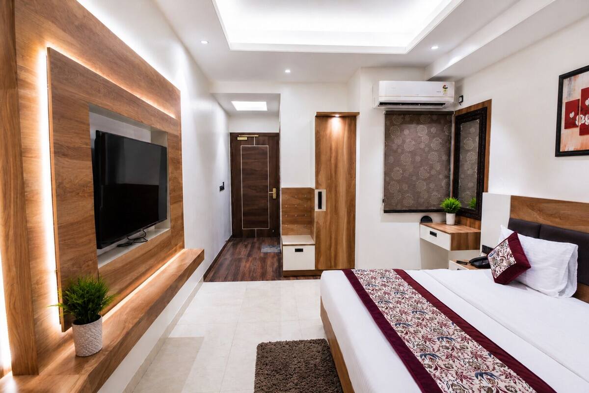 A modern bedroom with a TV, bedside table, bed, and a small plant.