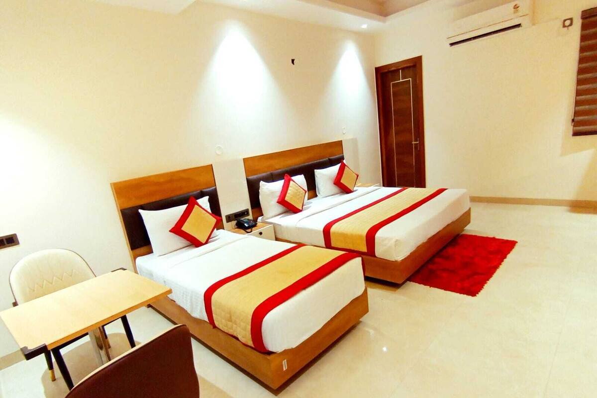 A hotel room with two beds, a desk, and a chair.