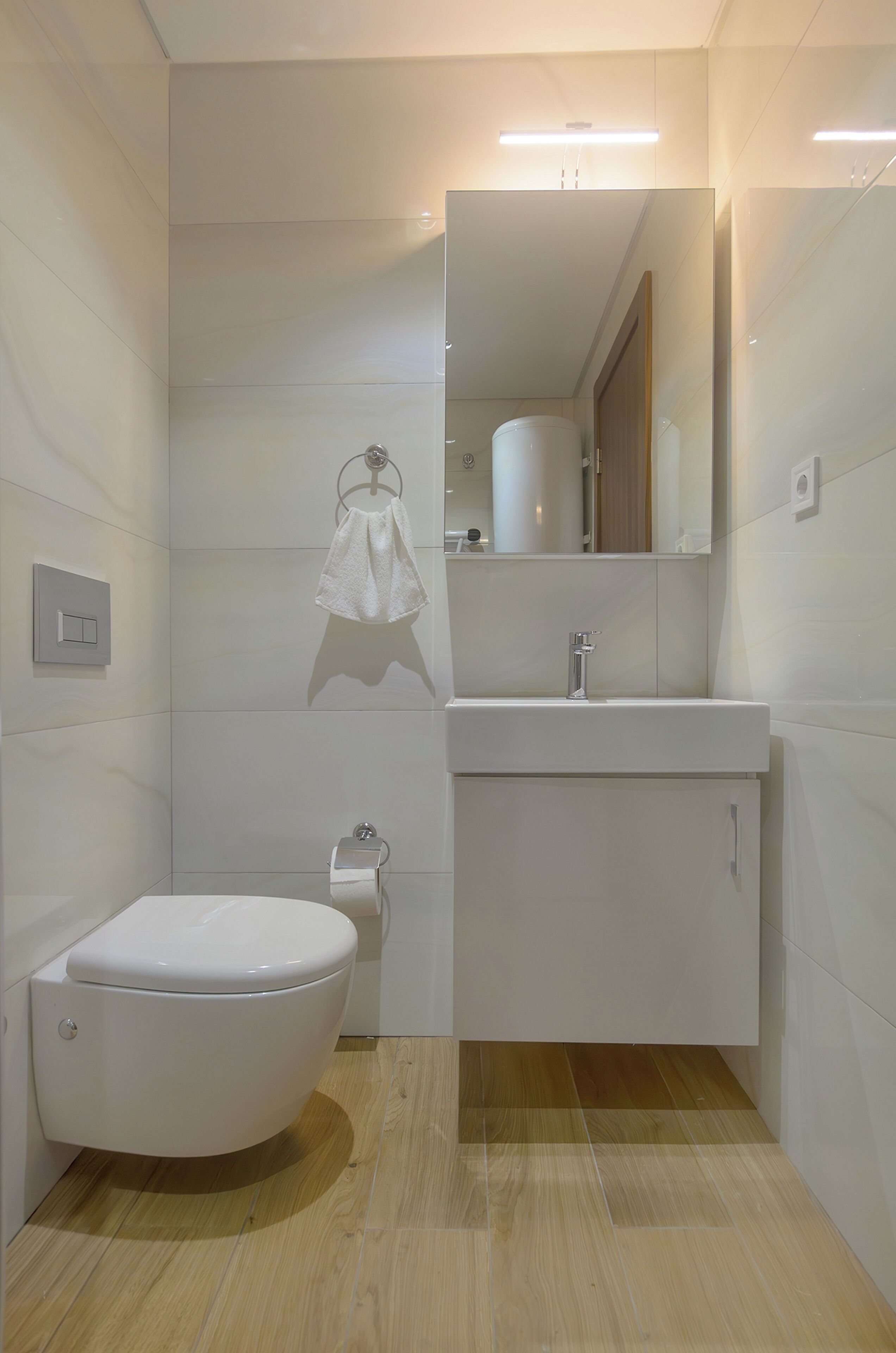 A modern bathroom with a toilet, sink, and mirror.