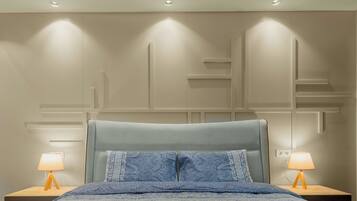 Un dormitorio con una cama, dos mesitas de noche con lámparas e iluminación empotrada en la pared.