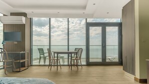A modern room with a bed, a TV, a desk, and a balcony with a table and chairs. - GLOBALSTAY Batumi View Apartments. Beach (Batumi)