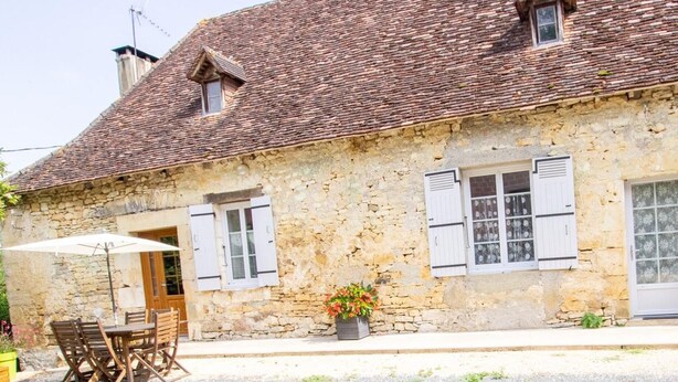 A stone building with a tiled roof, wooden shutters, and a small balcony. - Charming Country House in Tourtoirac, Pets Allowed (Tourtoirac)