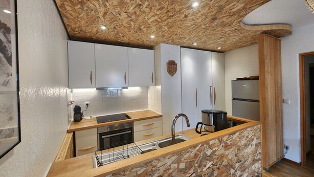 A modern kitchen with a stone countertop, wooden ceiling, and white cabinets. - Apartment with view and parking - 6 guests (Samoëns)