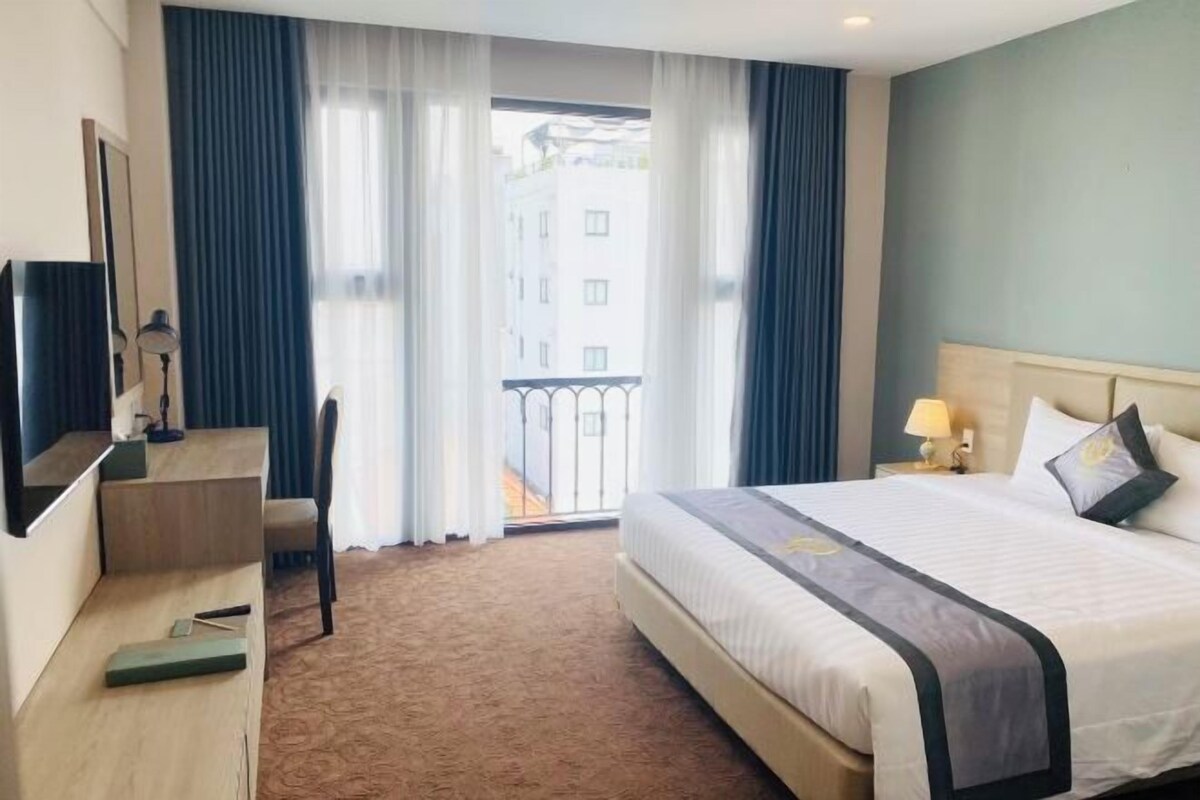 Habitación de hotel con cama, escritorio, silla y vista al exterior.