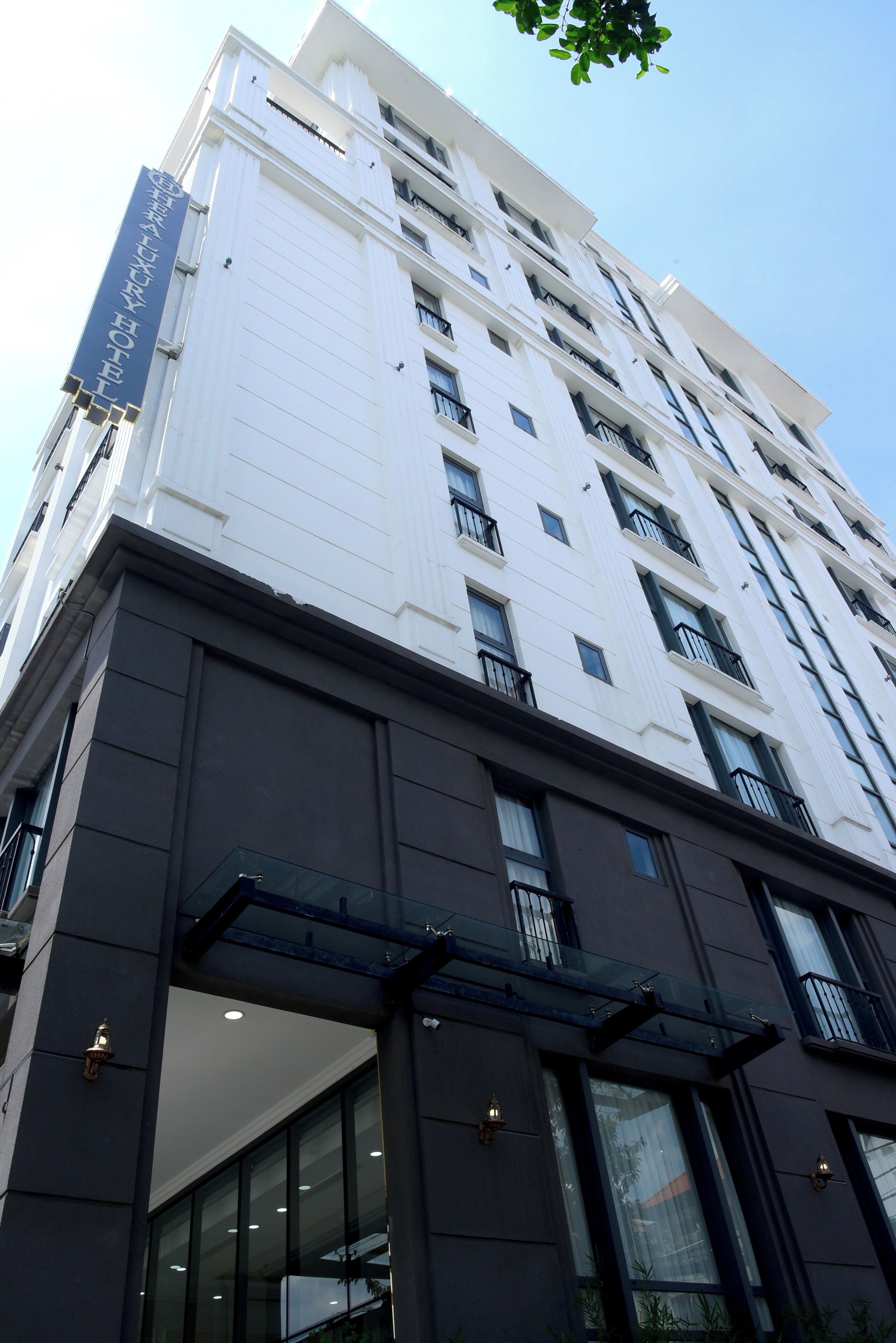 A modern hotel building with a prominent sign for the Grand Luxury Hotel.