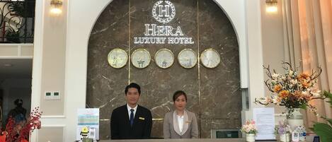 Eine Rezeption im Hera Luxury Hotel mit Marmorwand, Uhren und einem Schild.