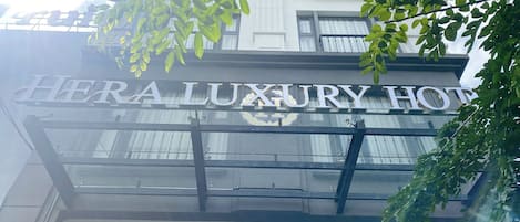 Un letrero de hotel que dice "HERA LUXURY HOTEL", con un diseño arquitectónico moderno y balcones visibles.
