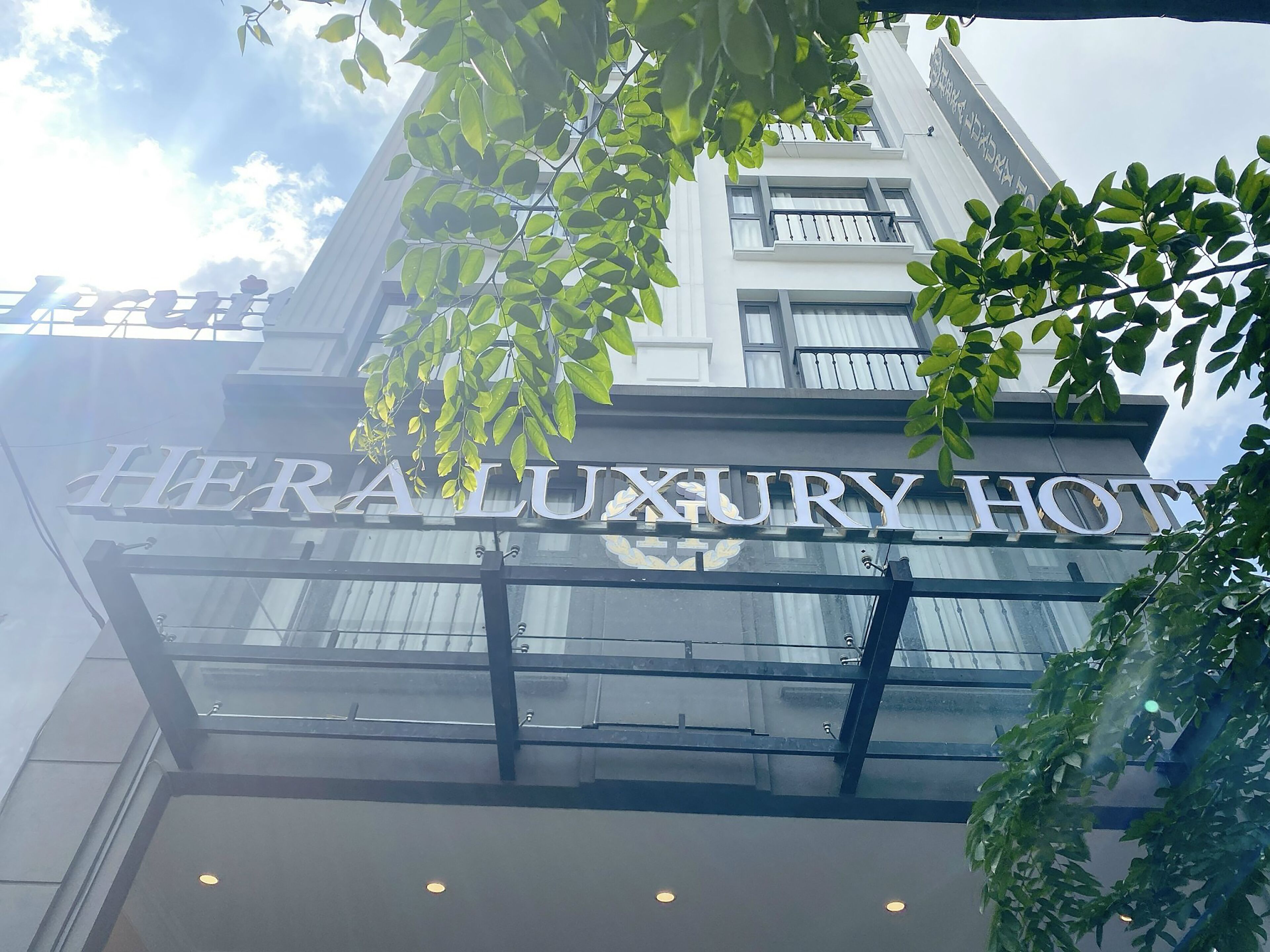 A hotel sign with the name "HERALUXURY HOTEL" and a glass entrance.
