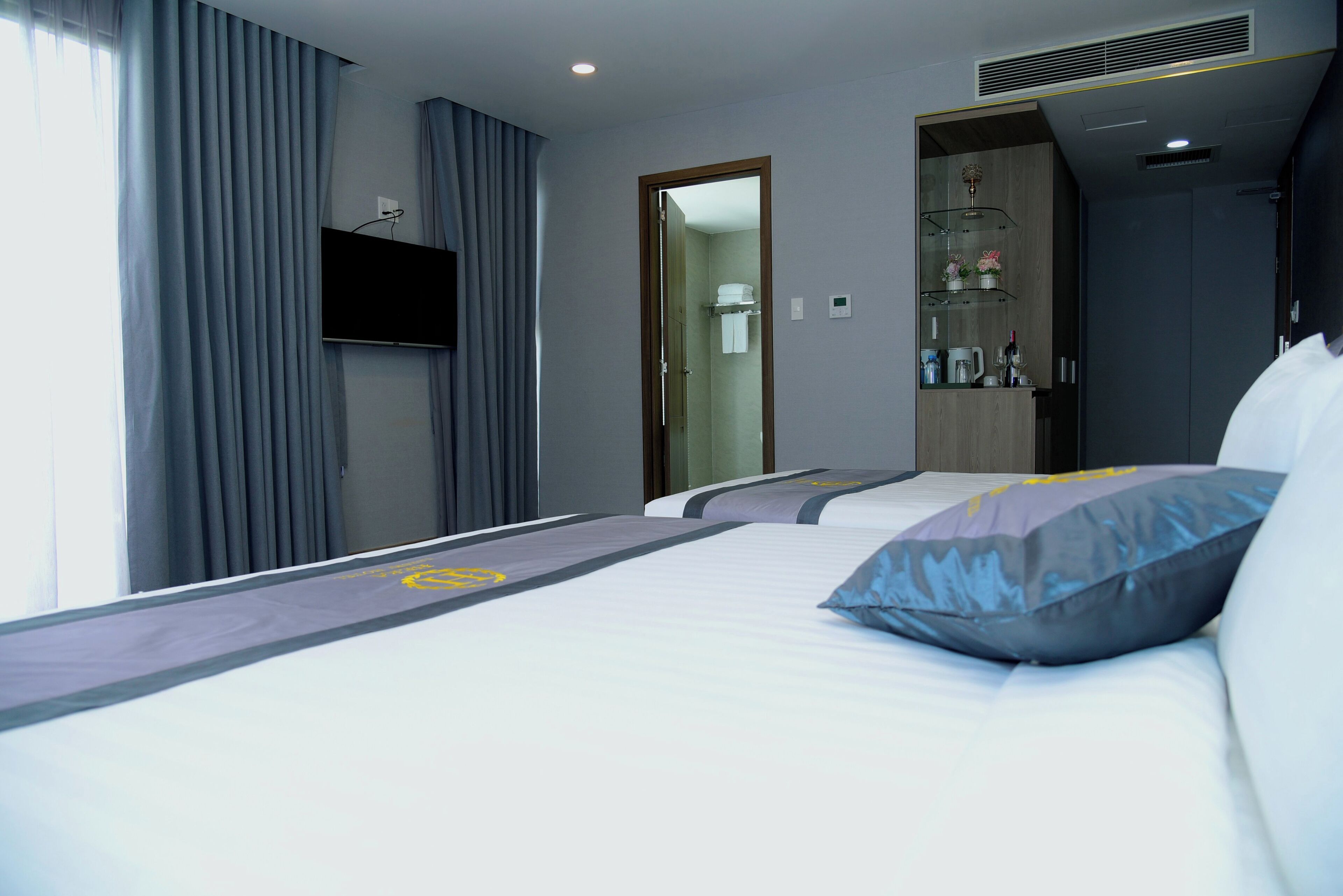 A hotel room with a bed, a TV mounted on the wall, and a bathroom visible through an open door.