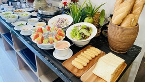 A buffet table with various dishes, including salads, fruits, and bread. - Hera Luxury Hotel (Ho Chi Minh City)