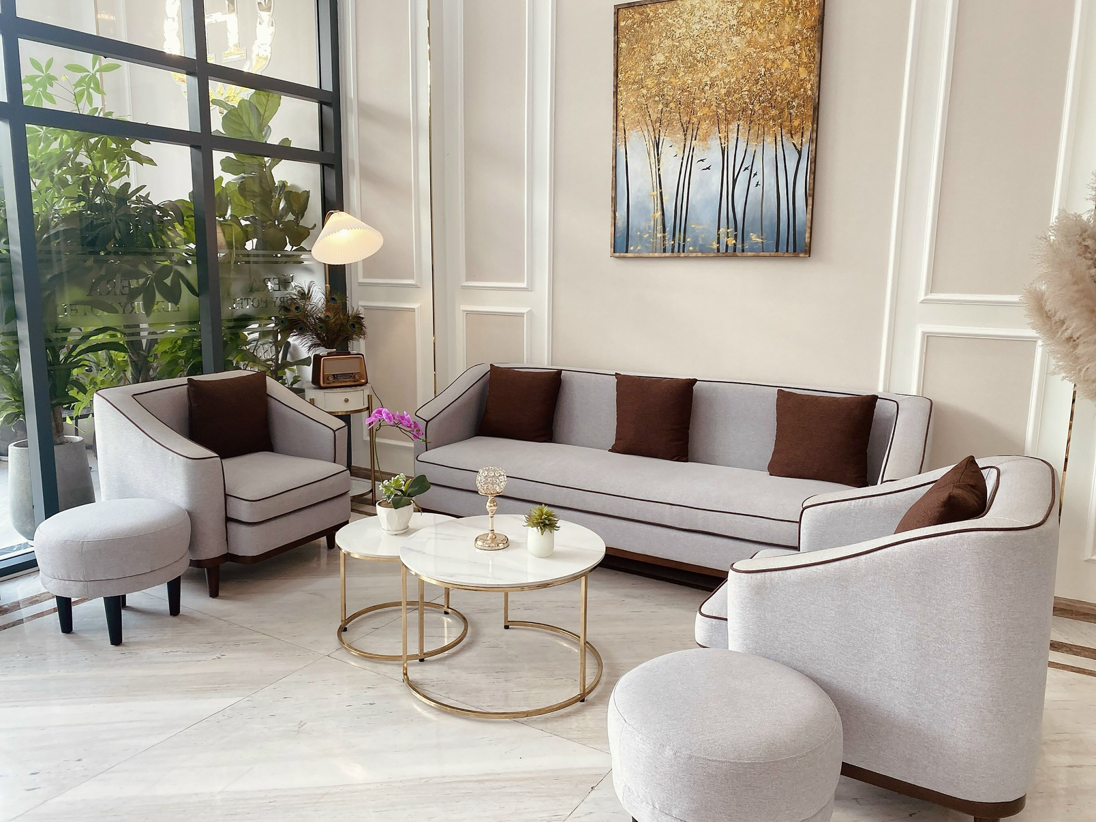 Una sala de estar moderna con un sofá gris, sillones a juego, una mesa de centro y un cuadro decorativo en la pared.