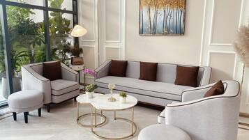 Una sala de estar moderna con un sofá gris, sillones a juego, una mesa de centro y un cuadro decorativo en la pared.