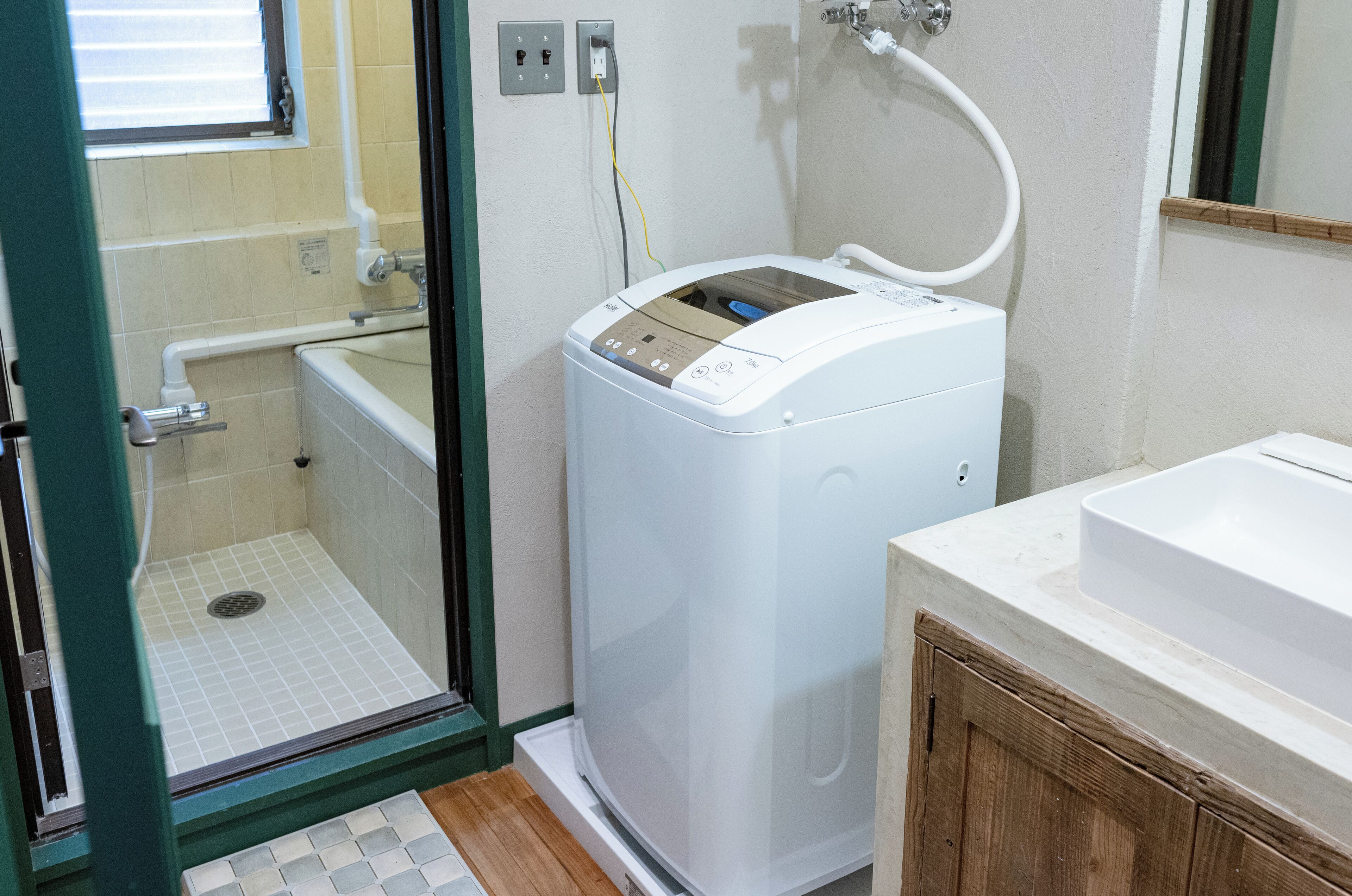 Une salle de bain compacte équipée d’un lave-linge et d’un sèche-linge intégrés, d’un petit espace douche et d’un lavabo.