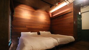 A room with a wooden floor and walls, a bed with white bedding, and a green door. - sunmalldai3 (Tokyo)