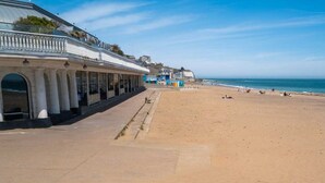 A beach with a building featuring columns and a balcony. - Recently refurbished and sleeping up to 4 guests, this stylish apartment offers stunning sea views, modern interiors, a fully equipped kitchen and a prime central location. Just moments from Ramsgate's Royal Harbour, beach, cafés and restaurants. (Kent)