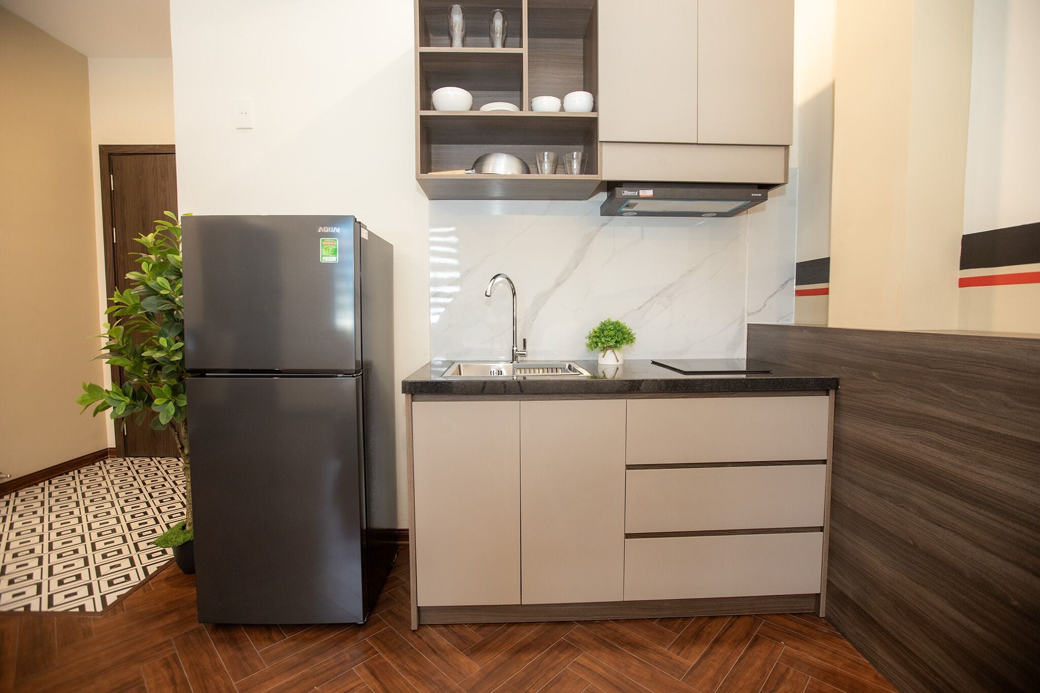 A compact kitchen with a refrigerator, sink, and cabinets.