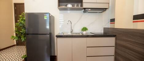 A compact kitchen with a refrigerator, sink, and cabinets.