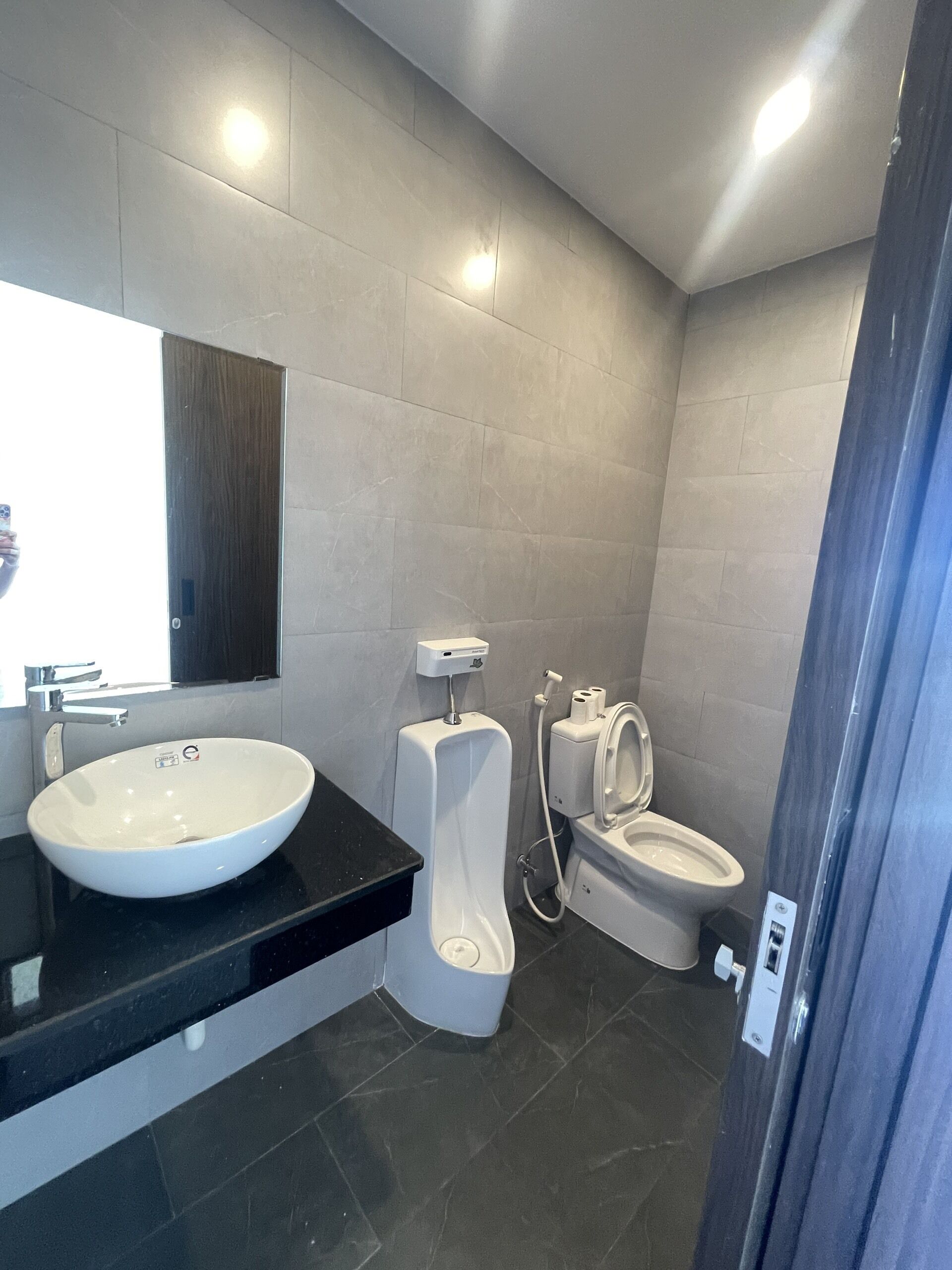 A modern bathroom with a large white sink, a toilet, and a bidet.