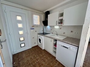 Uma cozinha compacta com máquina de lavar, pia e janela.