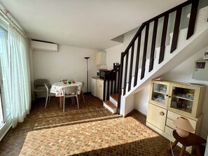 Um quarto com uma mesa de jantar, cadeiras, uma escada e um armário.