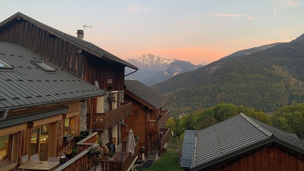A wooden chalet with a balcony overlooking a mountainous landscape.