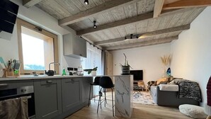 A modern kitchen with grey cabinets, a marble island, and a large window.