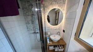 A bathroom with a glass-enclosed shower, a wooden vanity with a white sink, and a mirror above the sink.
