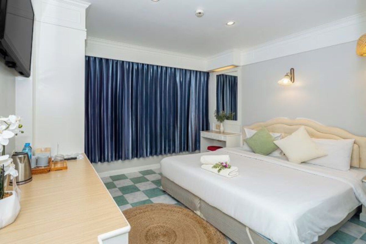 A hotel room with a bed, bedside table, and a TV.