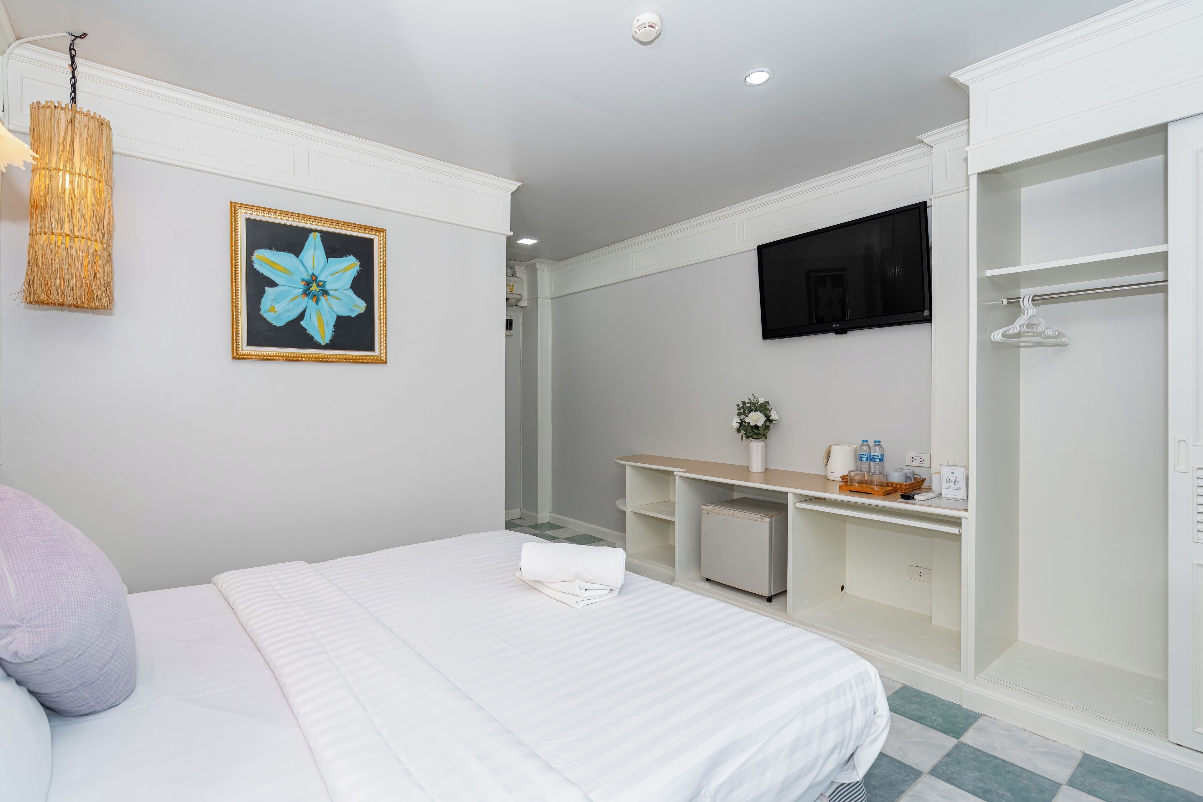 A hotel room with a bed, a desk, a TV, and a walk-in closet.