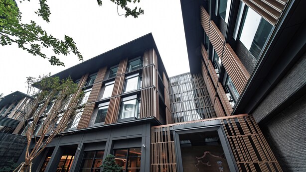 A modern building with multiple floors, large windows, and a courtyard with plants.