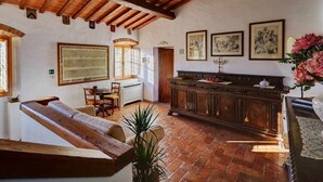 A rustic interior with a wooden bench, a dining table with chairs, a cabinet, and framed artwork on the walls. - Fichi Appartment (Firenze)