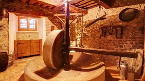 A rustic stone-walled room with a large wooden barrel press, wooden cabinets, and a stone fireplace. - Fichi Appartment (Firenze)