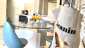 Una cocina moderna con una mesa de comedor de vidrio, sillas azules y un bolso colgante con el texto 'jeanmin'.
