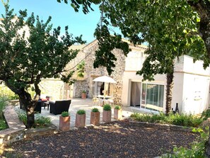 Un edificio de piedra con un patio, mesas al aire libre y plantas en macetas.